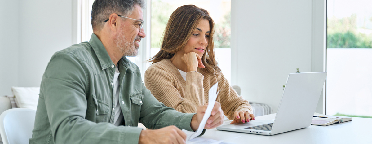 Mand Og Kvinde Ved Spisebord Kigger Paa Pc Ser Begejstret Ud