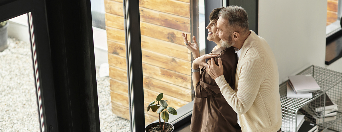 Par Holder Om Hinanden I Stuen Og Kigger Ud Af Vindue
